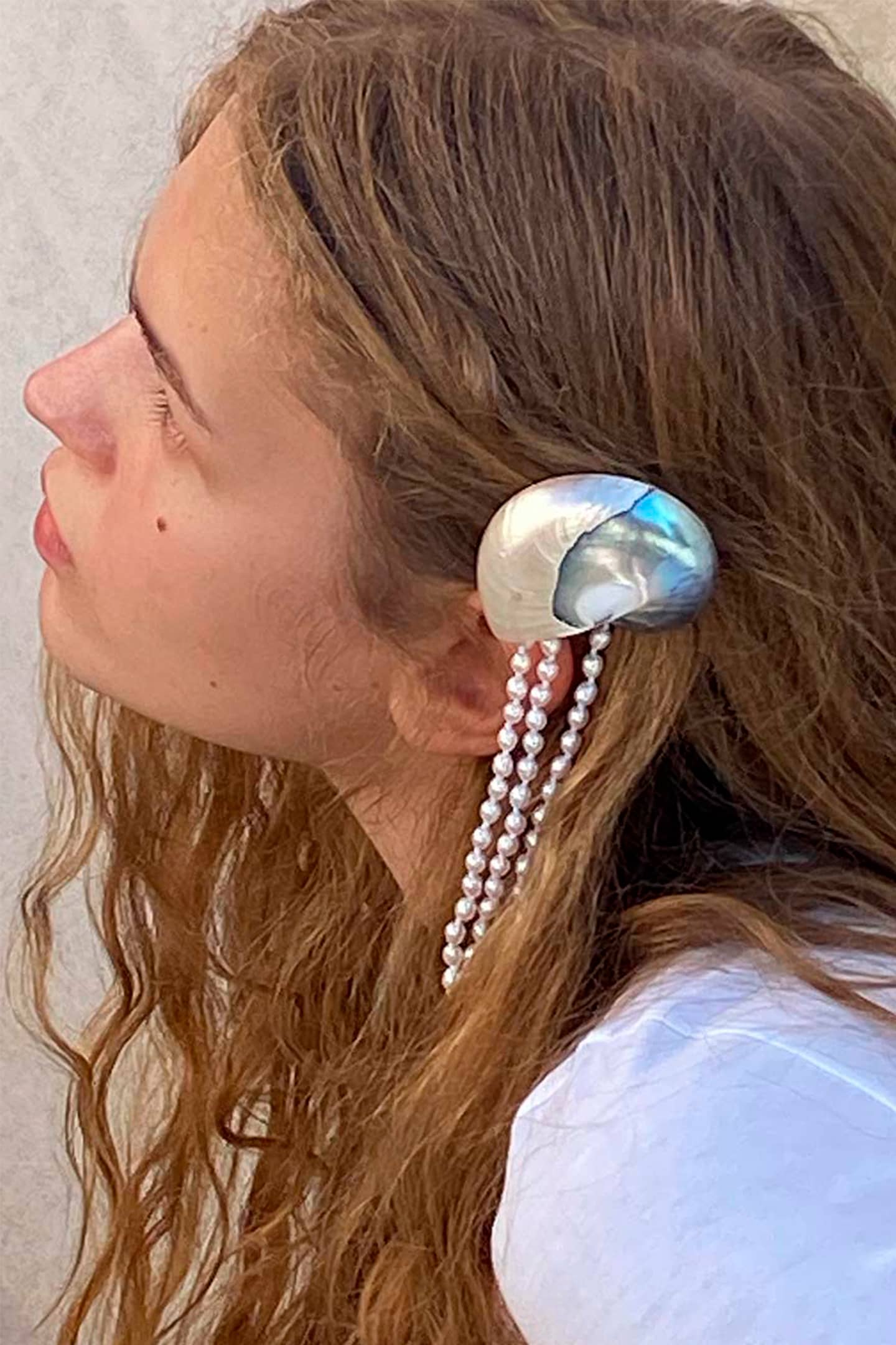 Profile view of handcrafted shell hair clip displaying the elegant combination of nautilus shell, pearls and gold plating