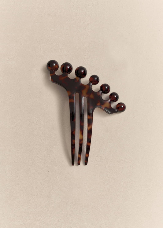 A handcrafted hair comb made from recycled acetate with sculptural lines designed for everyday wear.